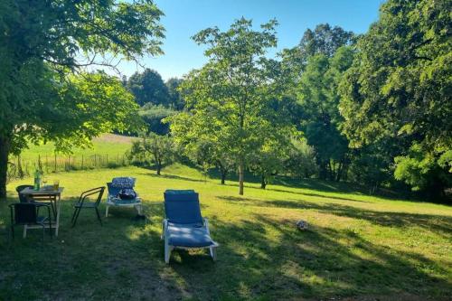 twee stoelen en een tafel in een veld met bomen bij Holiday Home Vito in Stubička Slatina