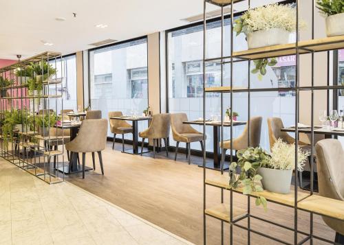 a restaurant with tables and chairs and windows at Catalonia Barcelona 505 in Barcelona