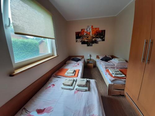 two beds in a room with a window at domek Drewniany na wiejskiej in Lubiatowo