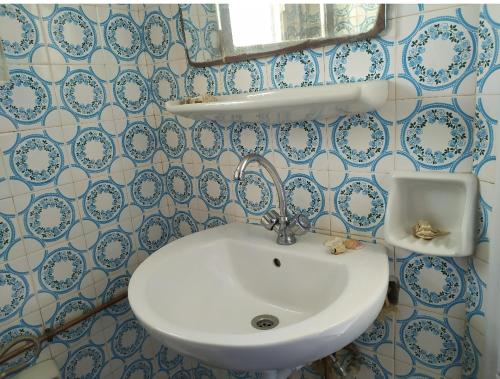 a white sink in a bathroom with blue and white tiles at stone house in Kathlikaros in Mési