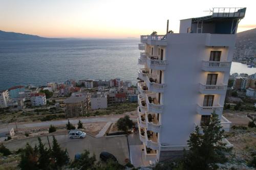 a white building with balconies on it next to the water at Sky Way SKK Luxury Apartments in Sarandë