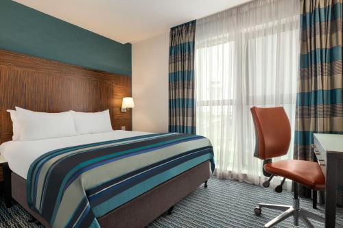 a hotel room with a bed and a desk and a chair at Holiday Inn Birmingham Airport - NEC by IHG in Bickenhill