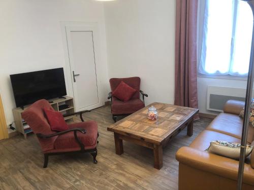 a living room with chairs and a table and a tv at Les Maisons du Conflent, maisons familiales en pierre au coeur des remparts in Villefranche-de-Conflent