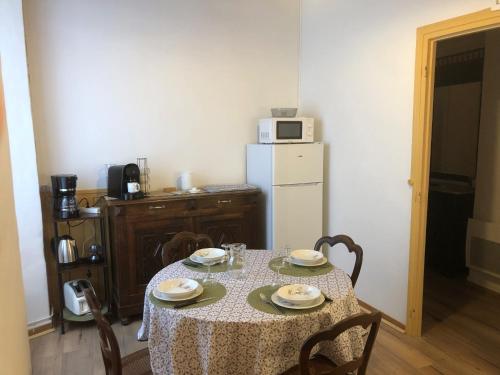 a kitchen with a table with chairs and a refrigerator at Les Maisons du Conflent, maisons familiales en pierre au coeur des remparts in Villefranche-de-Conflent
