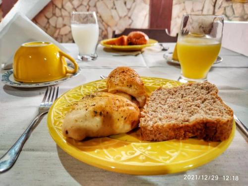 a yellow plate of food with bread and orange juice at Pousada Carpediem in Morro de São Paulo