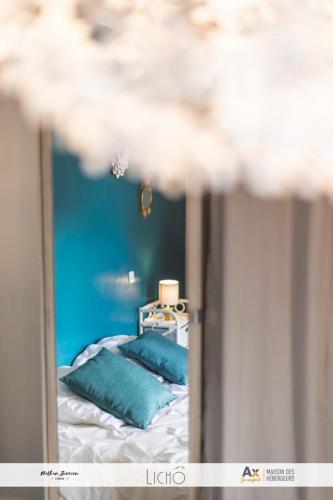 a reflection of a bed with blue pillows in a mirror at Appartement VILLA PAULA Ax-les-Thermes in Ax-les-Thermes