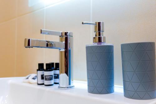 a bathroom sink with a bottle of soap and a faucet at Sky Way SKK Luxury Apartments in Sarandë
