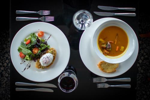 a table with two plates of food and a bowl of soup at Cala di Volpe Boutique Hotel in Montevideo