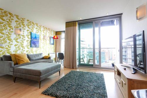 a living room with a couch and a large window at Iconic Luxury Manchester Apartment in Manchester