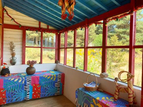 eine abgeschirmte Veranda mit Fenstern und blauer Decke in der Unterkunft Gîte Ranch Le Serpolet in Les Angles