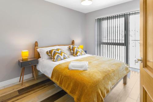 a bedroom with a bed with a yellow blanket and a window at Spacious and Modern Mountain View Apartment in Ebbw Vale