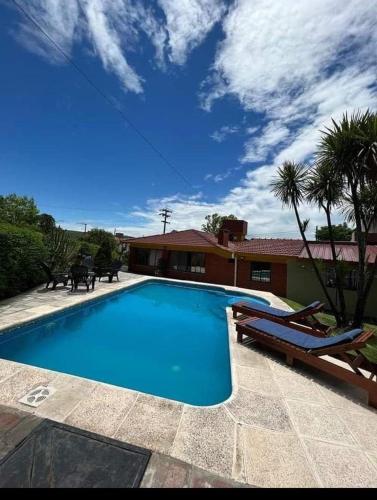 una piscina con 2 tumbonas y una casa en Ebenezer en Valle Hermoso
