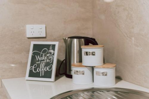 a counter with a coffee pot and four containers on it at Olinda Sandstone Apartment 2 Bedroom Spa bath in Olinda