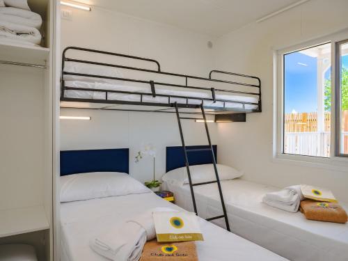 a bedroom with two bunk beds and a window at Club del Sole Pini Boutique Resort in Punta Marina