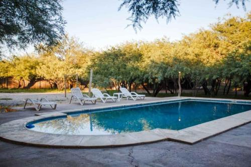 a swimming pool with two chairs and a table at Estancia Rio de Arena 