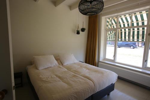 un letto in una camera con una grande finestra di Recreatieappartement BoerdeRijlst - De Kamer a Sint Nicolaasga