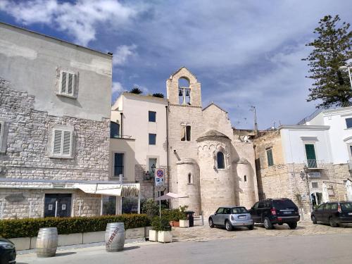 an old stone building with a church and cars parked at Monolocale prezioso in Trani