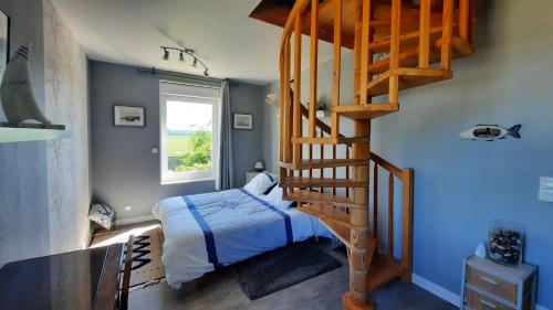 1 dormitorio con 1 cama y escalera de caracol en Gite galets et bois flottés proche mer gold beach meublé de tourisme 4 étoiles, en Meuvaines