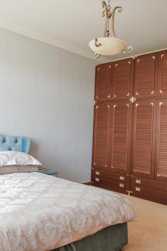 a bedroom with a bed and a chandelier and wooden cabinets at Villa Avoti in Sigulda