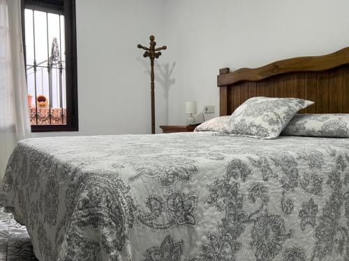 1 dormitorio con 1 cama con manta y cruz en La Casa de Adela, en Táliga