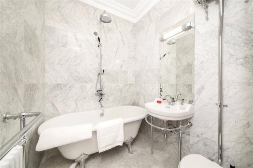 a white bathroom with a tub and a sink at Luxurious 1-bedroom apartment. Indoor Fireplace in South Norwood