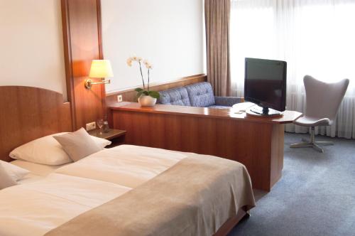 a hotel room with a bed and a desk with a television at Hotel Germania in Reutlingen