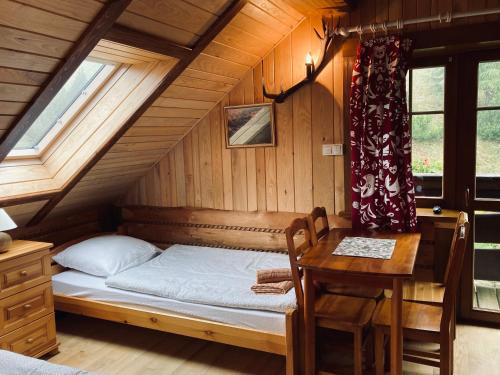 ein Schlafzimmer mit einem Bett und einem Tisch im Dachgeschoss in der Unterkunft Hubertówka pod Jaworzem in Żmiąca