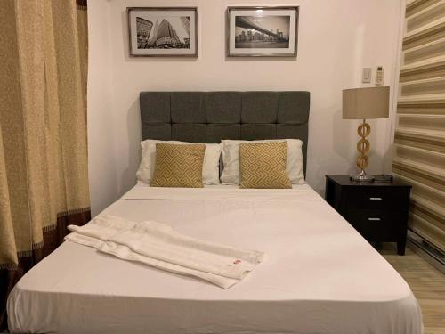 a bedroom with a white bed with a black headboard at Azure Condotel in Manila