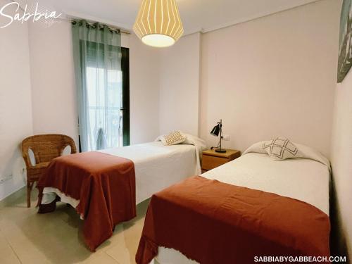 Habitación con 2 camas, lámpara y ventana en Apartment Sabbia by Gabbeach Valencia, en Valencia