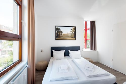 ein weißes Bett in einem Zimmer mit Fenster in der Unterkunft Hotel Garni am Olgaeck in Stuttgart