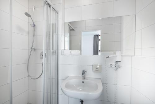 biała łazienka z umywalką i prysznicem w obiekcie Hotel Garni am Olgaeck w Stuttgarcie