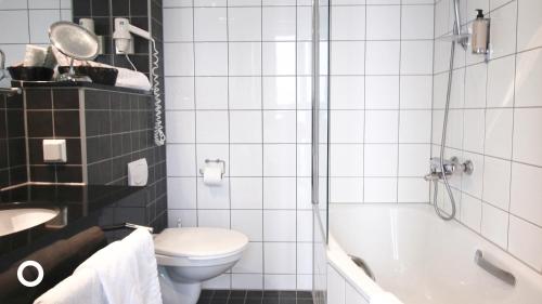a bathroom with a toilet and a tub and a sink at Center Hotels Arnarhvoll in Reykjavík