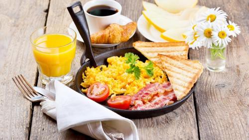 a breakfast of eggs bacon tomatoes and toast and a glass of orange juice at The Landmark Banjara Hills - Hyderabad in Hyderabad