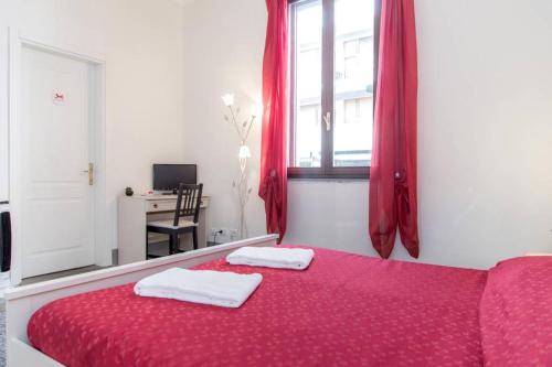 Guest House L'Aranceto في فلورنسا: غرفة نوم بسرير احمر وعليها منشفتين
