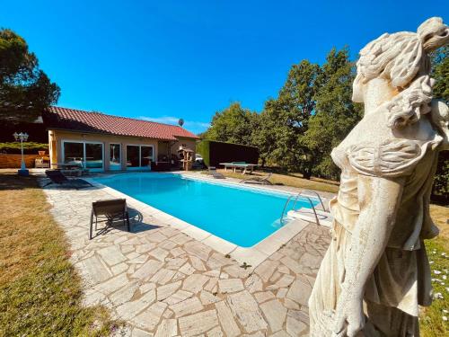 uma estátua de um anjo ao lado de uma piscina em La Villa Perroquet em Poncins