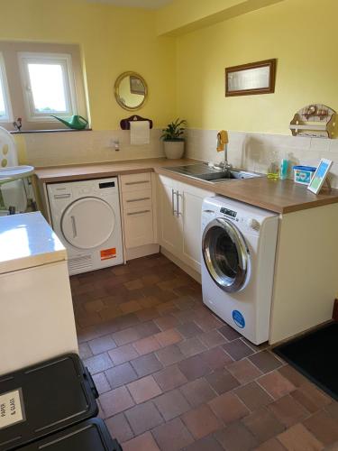 a kitchen with a washing machine and a sink at Cotswolds Luxury House in Central Bourton Large Sleeps 2-11. Pet Friendly. in Bourton on the Water