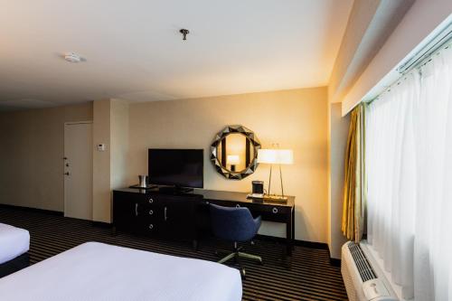 a hotel room with a desk and a mirror at APA Hotel Woodbridge in Iselin