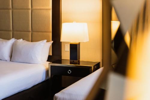 a hotel room with a bed and a lamp on a night stand at APA Hotel Woodbridge in Iselin