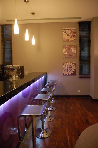 a row of stools in a bar with purple lighting at Hotel Tivoli Maputo in Maputo