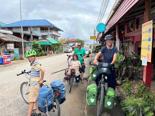 um grupo de pessoas andando de bicicleta por uma rua em Little Hostel em Ban Houayxay