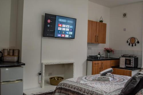 cocina con mesa y TV en la pared en Bv Comfy Studio At Maningham Lane Bradford en Bradford