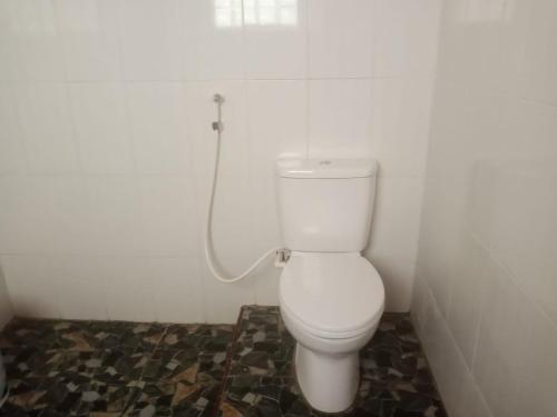 a bathroom with a white toilet with a hose at Raja Guest House - Jungle Trekking & Tours Bukit Lawang Sumatra in Bukit Lawang