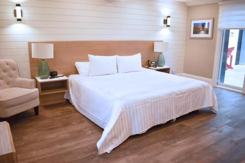 a bedroom with a large white bed and a chair at Colonial Hotel & Suites in Grand Bend
