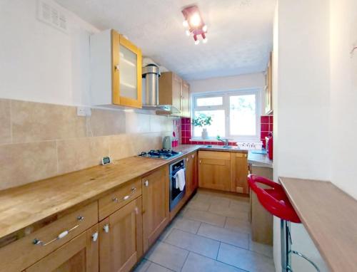 una cocina con armarios de madera y una silla roja. en Cozy 4 Bedroom House in Smethwick with 4 bathrooms perfect for contractors and families en Birmingham