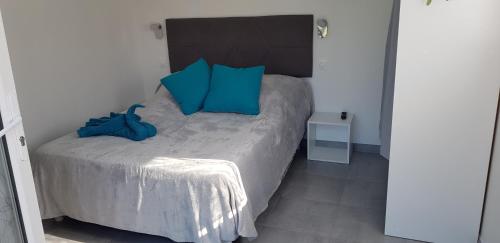 Un dormitorio con una cama con almohadas azules. en Chambre d'hôtes Entre-deux Lacs, en Biscarrosse