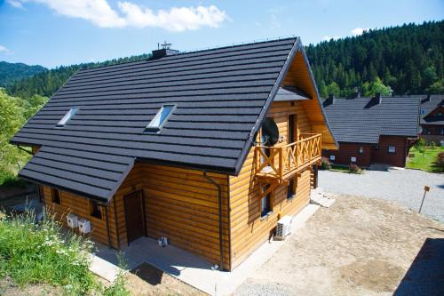 a large log cabin with a black roof at Solny - Resort w Bieszczadach in Cisna