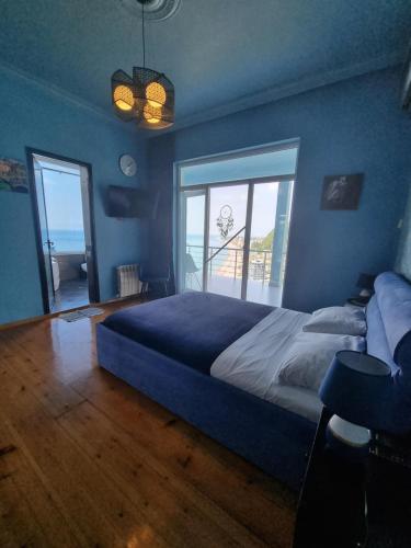 a bedroom with a large bed and a large window at Calypso Kvariati Hotel in Kvariati
