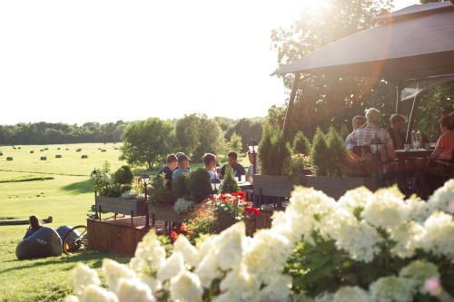 a group of people sitting at tables in a field with flowers at Abzali Hotel and Restaurant with self check-in in Ādaži