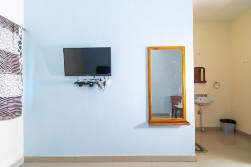 een spiegel en een tv op een witte muur bij Dwarka Residency in Mahabalipuram