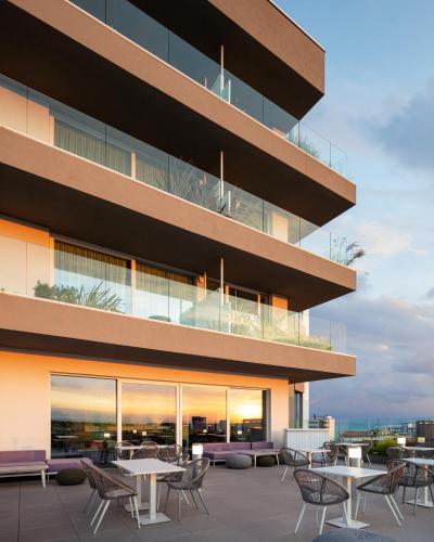an exterior view of a building with tables and chairs at J44 Lifestyle Hotel in Lido di Jesolo